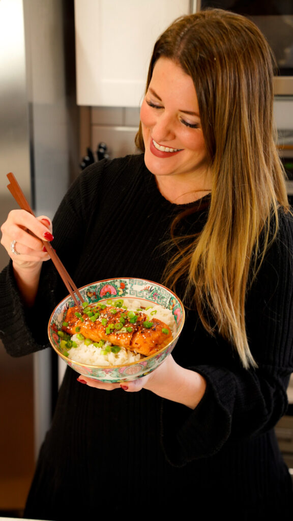 Woman eating Hot Honey Sriracha Asian Marinade for Salmon in a bowl with rice.