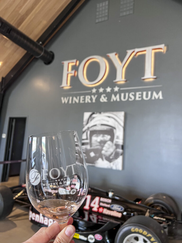 Glass of Foyt wine by a racecar