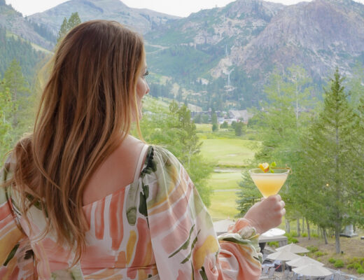 Woman with a cocktail at a restaurant with beautiful lake tahoe mountain views.
