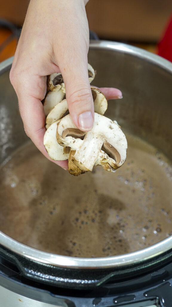 Mushrooms being added to the braising liquid for beef cheeks.