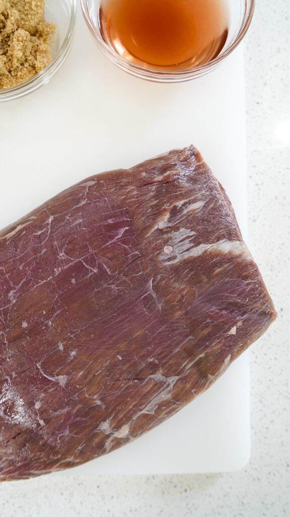 Flank steak on a cutting board prior to going into an air fryer.