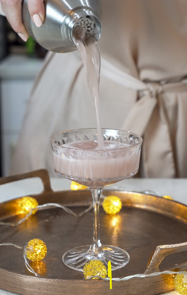 French martini recipe being poured from a cocktail shaker into a coupe glass.