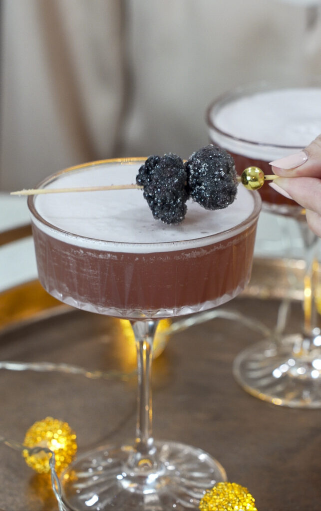 Garnishing a French martini cocktail with a sugared black raspberry.