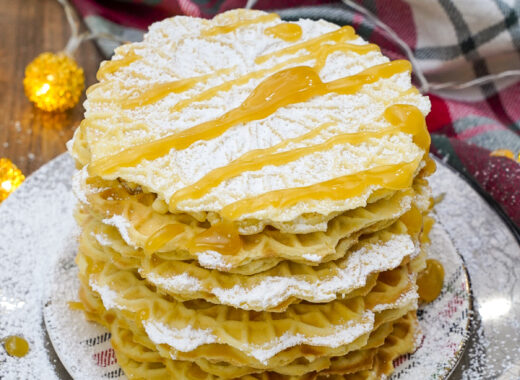 Stack of lemon pizzelle cookies with lemon curd and powdered sugar.