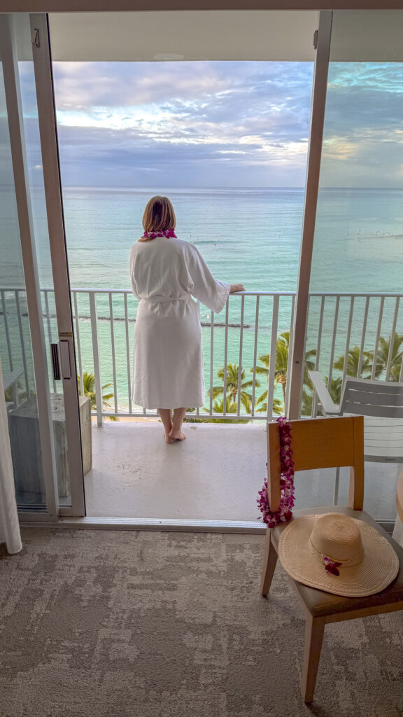 Woman standing on the oceanfront balcony of the 'Alohalani resort in Oahu, Hawaii.