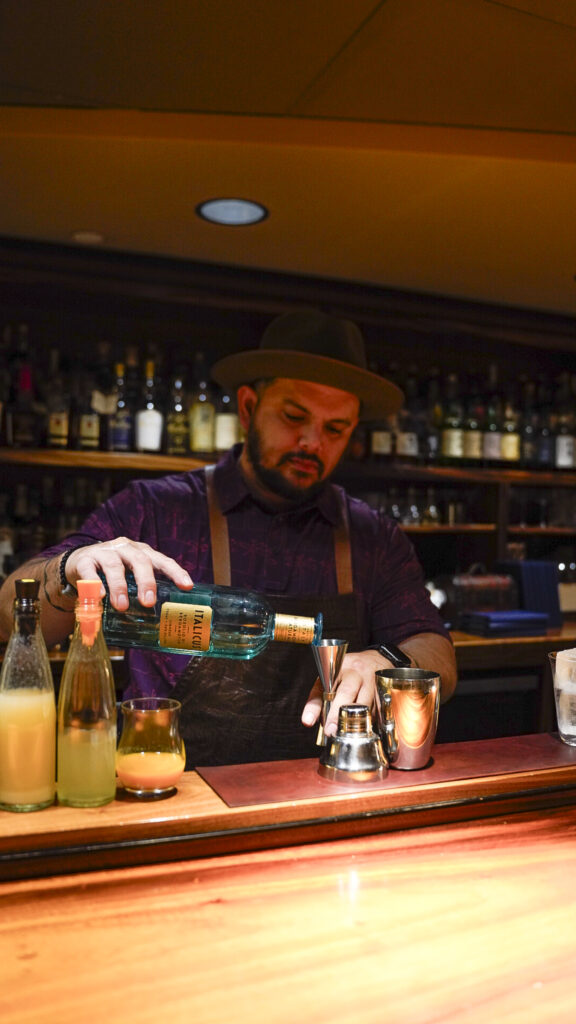 A bartender making a drink at bar leather apron, a romantic thing to do in Oahu, Hawaii.