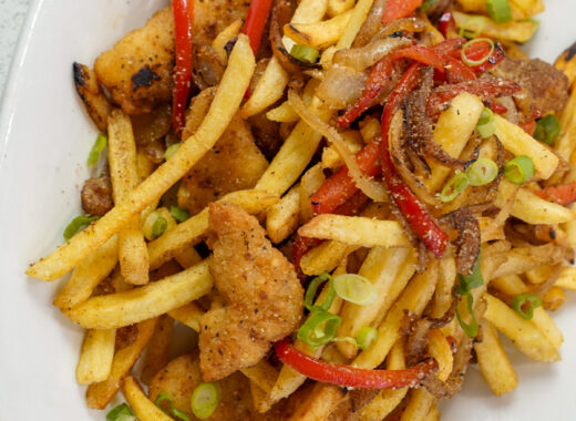 Irish spice bag recipe on a platter with chicken, fries, peppers, and onions.