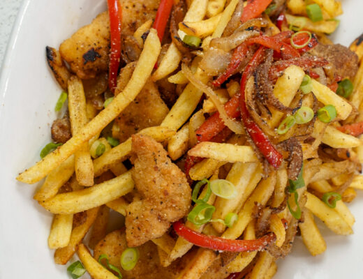 Irish spice bag recipe on a platter with chicken, fries, peppers, and onions.