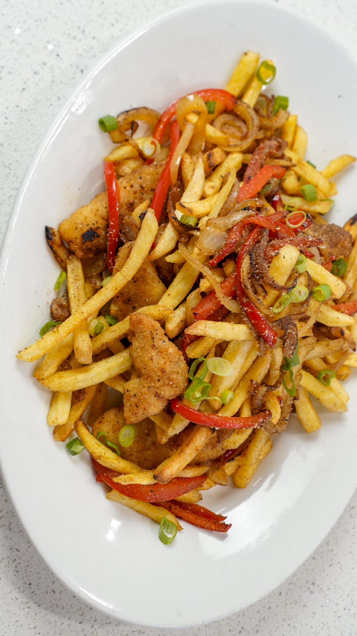 Irish spice bag recipe on a platter with chicken, fries, peppers, and onions.