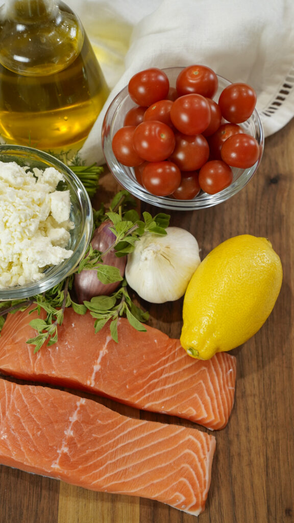 Ingredients for baked Mediterranean salmon recipe on a cutting board.