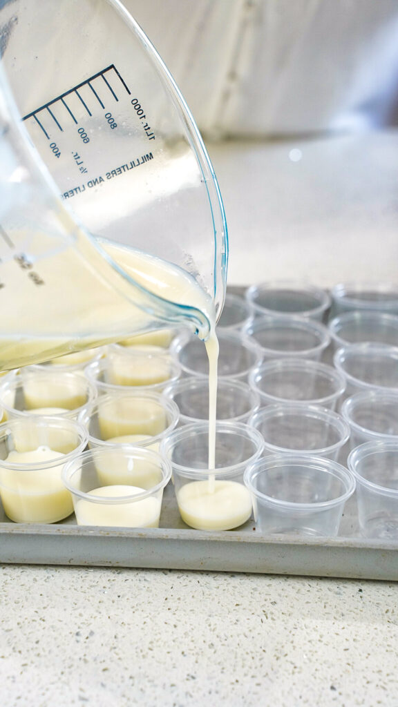 A white layer being poured into shot glasses for a Pina Colada Jello Shots Recipe.