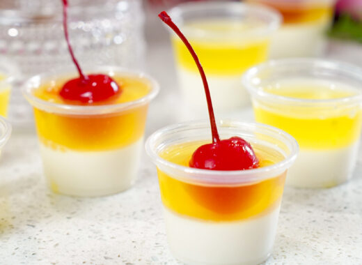 Layered Pina Colada Jello Shots Recipe topped with cherries.