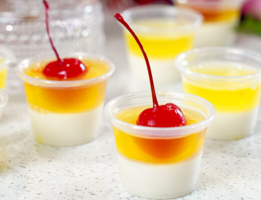 Layered Pina Colada Jello Shots Recipe topped with cherries.