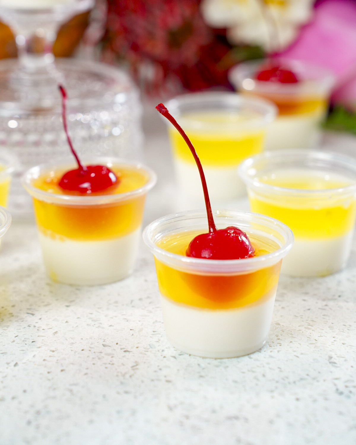 Layered Pina Colada Jello Shots Recipe topped with cherries.