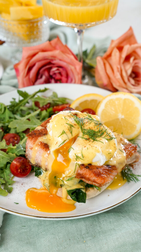 Egg yolk running out of a seared salmon eggs benedict recipe on a plate.