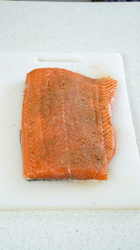 Seasoned salmon on a cutting board for a seared salmon eggs benedict recipe.