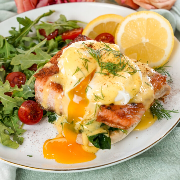 Seared salmon eggs benedict recipe on a plate with a salad.