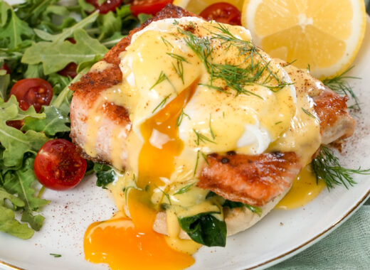 Seared salmon eggs benedict recipe on a plate with a salad.