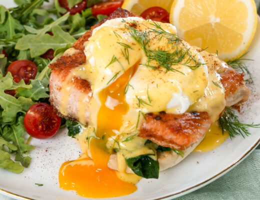 Seared salmon eggs benedict recipe on a plate with a salad.
