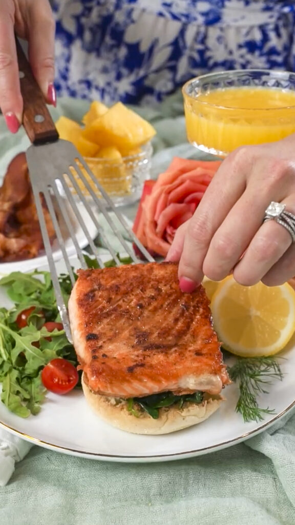 Assembling a seared salmon eggs benedict recipe on a plate.