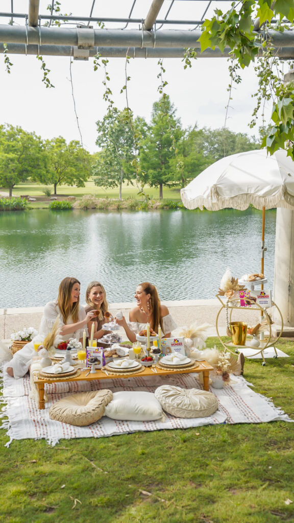 Women with platters of wonderbread sweets at a luxury picnic.