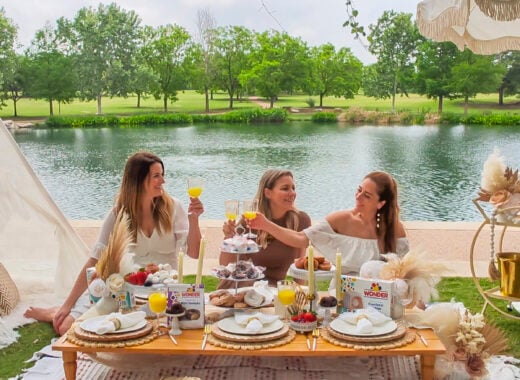 Women with platters of wonderbread sweets at a luxury picnic.