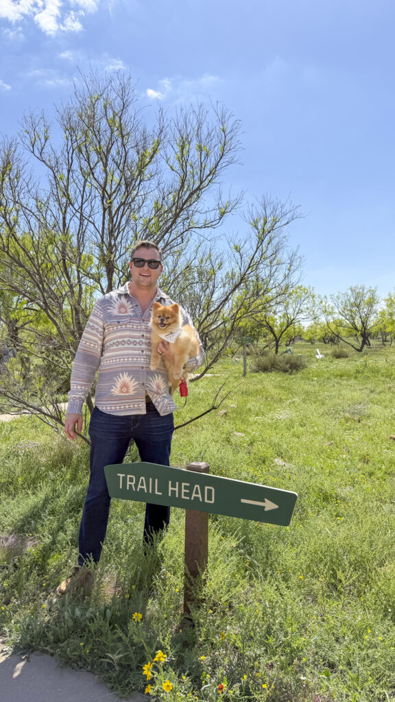 Man and a dog next to a trailhead sign in Amarillo.