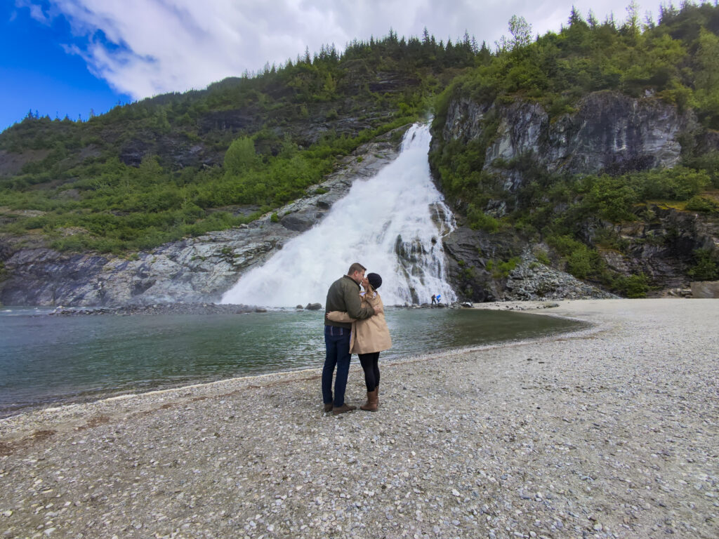 Couple standing at Nugget Falls, one of the best things to do in Juneau, Alaska.