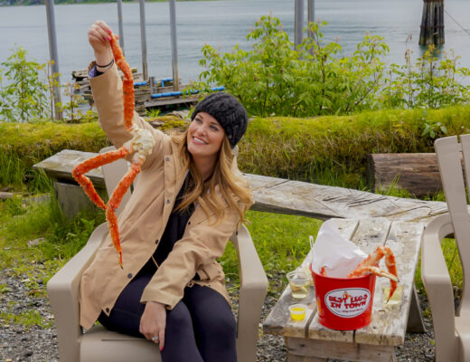 Woman holding a crab leg from Tracy's Crab Shack in Juneau, Alaska.