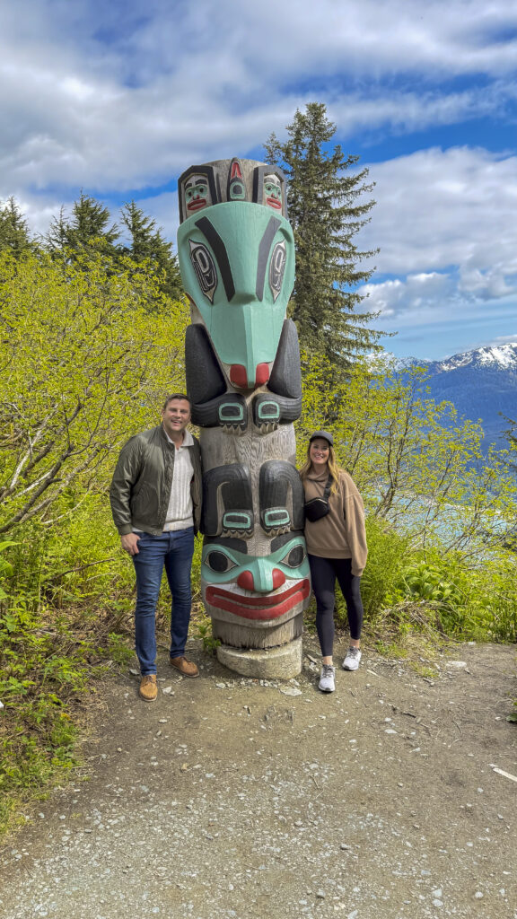 Couple hiking next to a totem pole, one of the things to do in Juneau, Alaska.