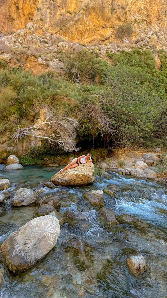 Woman sunbathing on a boulder at the hidden waterfall gorge near Rethymno Crete.