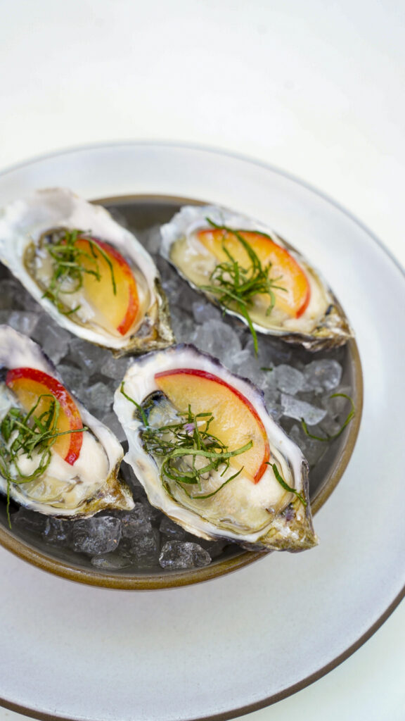 Oysters topped with peach slices.