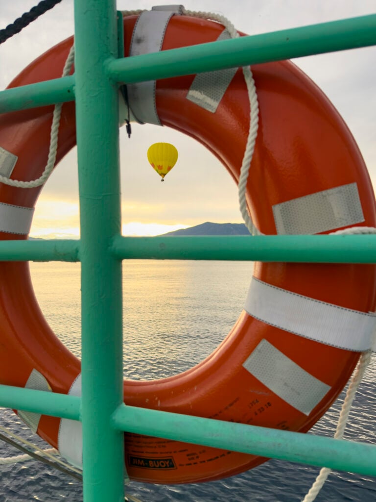 View of a hot air balloon through a lifesaver ring on a boat.