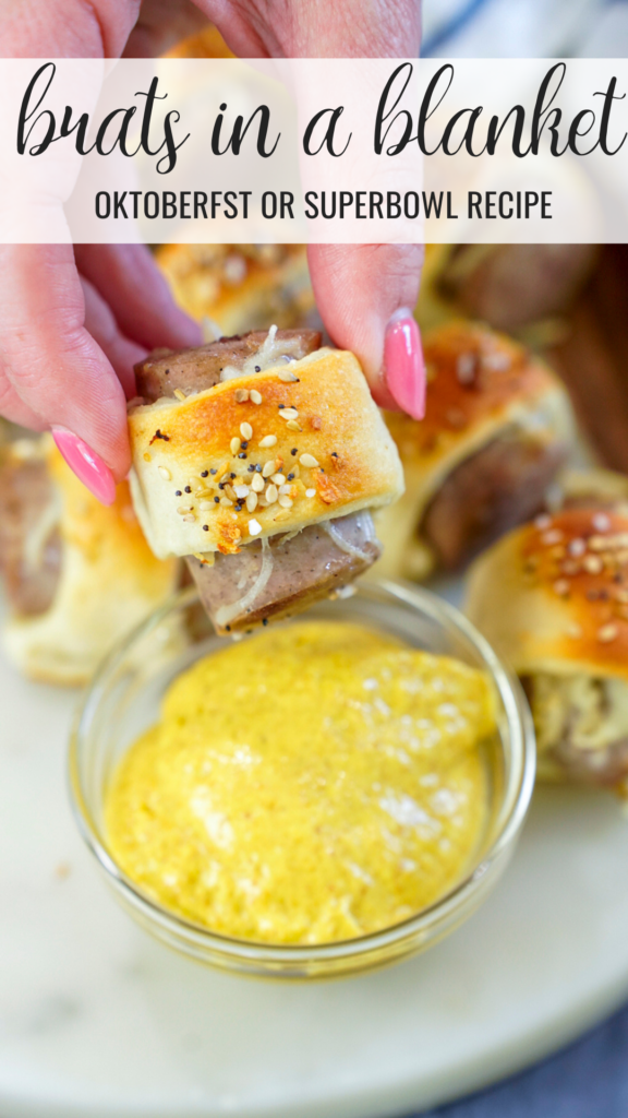 Brats in a blanket recipe for an oktoberfest party being dipped into mustard.