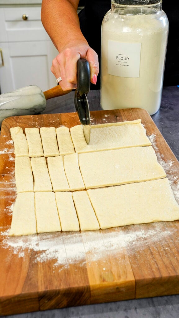 Cutting dough for a brats in a blanket recipe for an oktoberfest party.