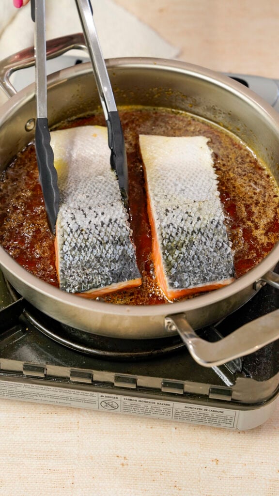 Salmon being placed in a skillet for a Vietnamese caramelized salmon recipe.