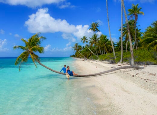 Couple laying on a palm tree in Fakarava, a stop on the Windstar Tahiti French Polynesia cruise.