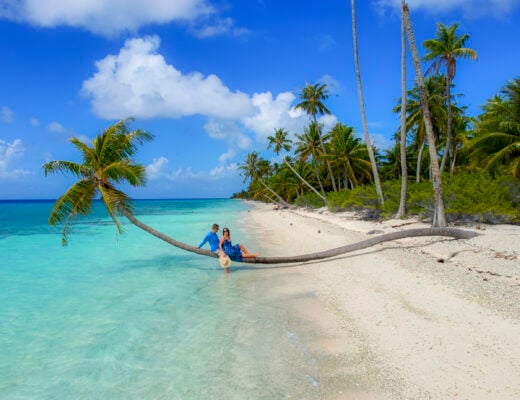 Couple laying on a palm tree in Fakarava, a stop on the Windstar Tahiti French Polynesia cruise.