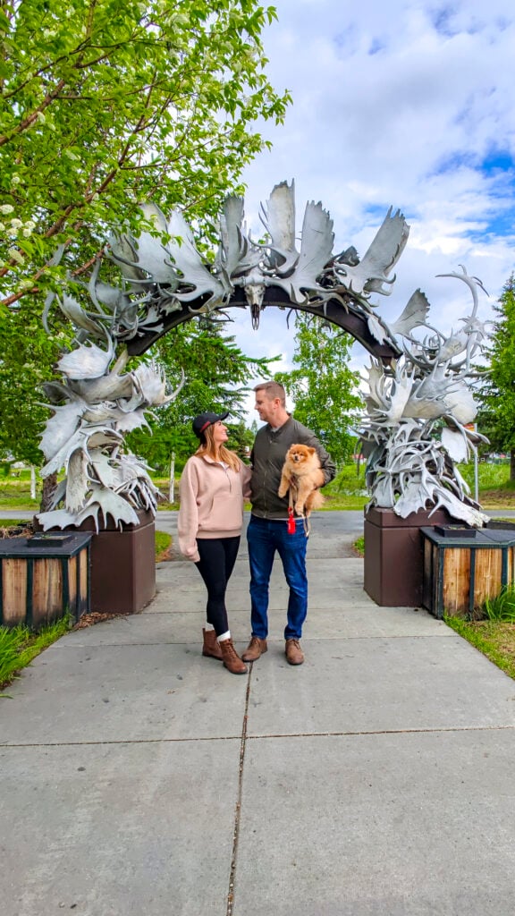 Couple with a dog under the Antler Arch, one of the best things to do in Fairbanks Alaska in the summer.