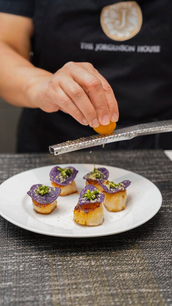 Woman garnishing scallops at the Jorgenson House cooking class in Juneau, Alaska.
