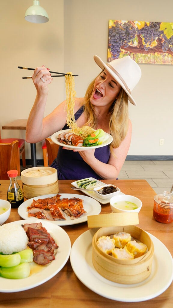 Woman holding up Roasted Duck Noodles, one of the best restaurants and bars in Reno.